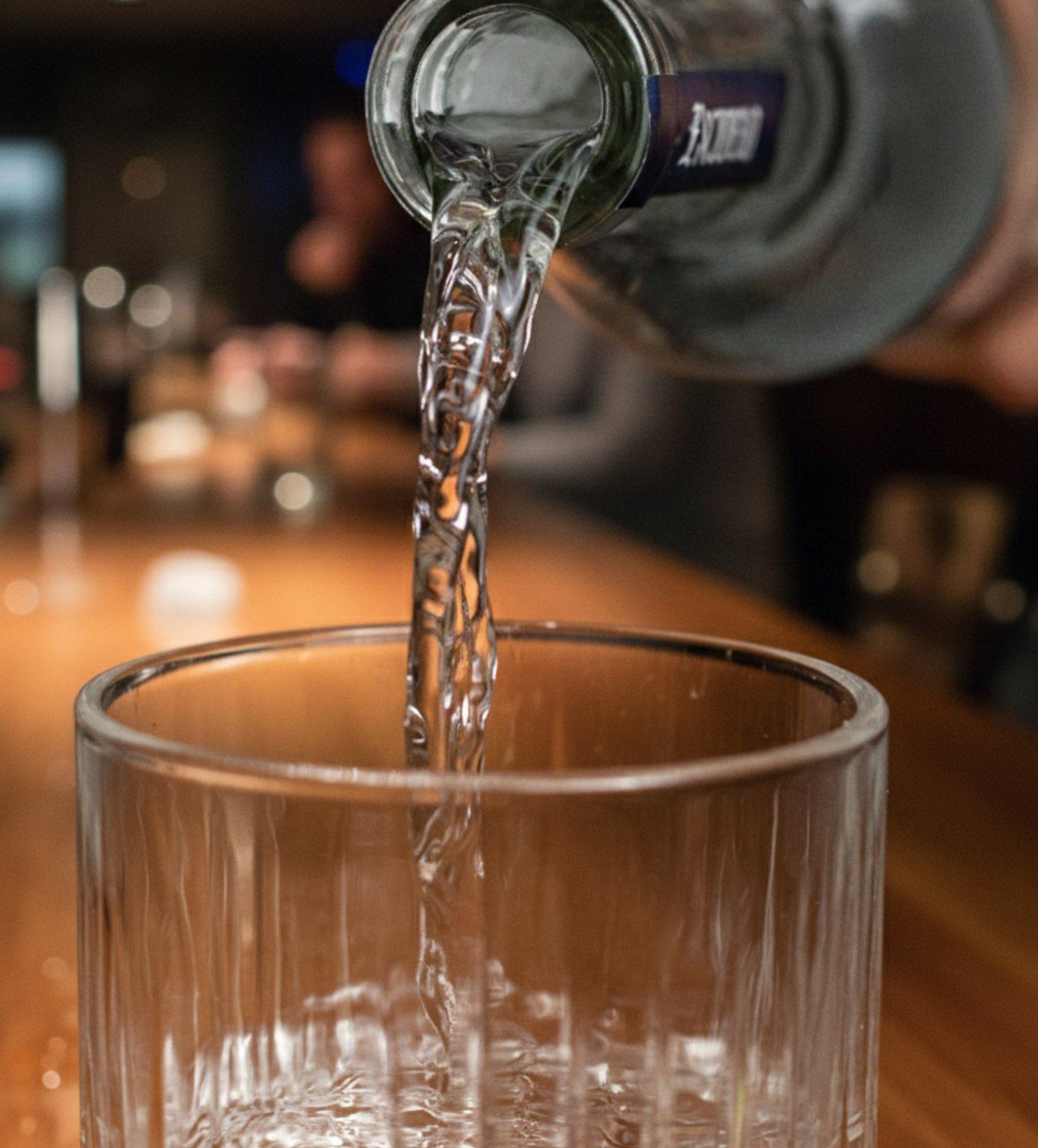 Tequila Escudero cayendo de la botella a un vaso, sobre la barra